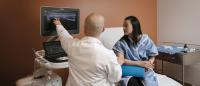 Physician points to ultrasound screen while patient watches